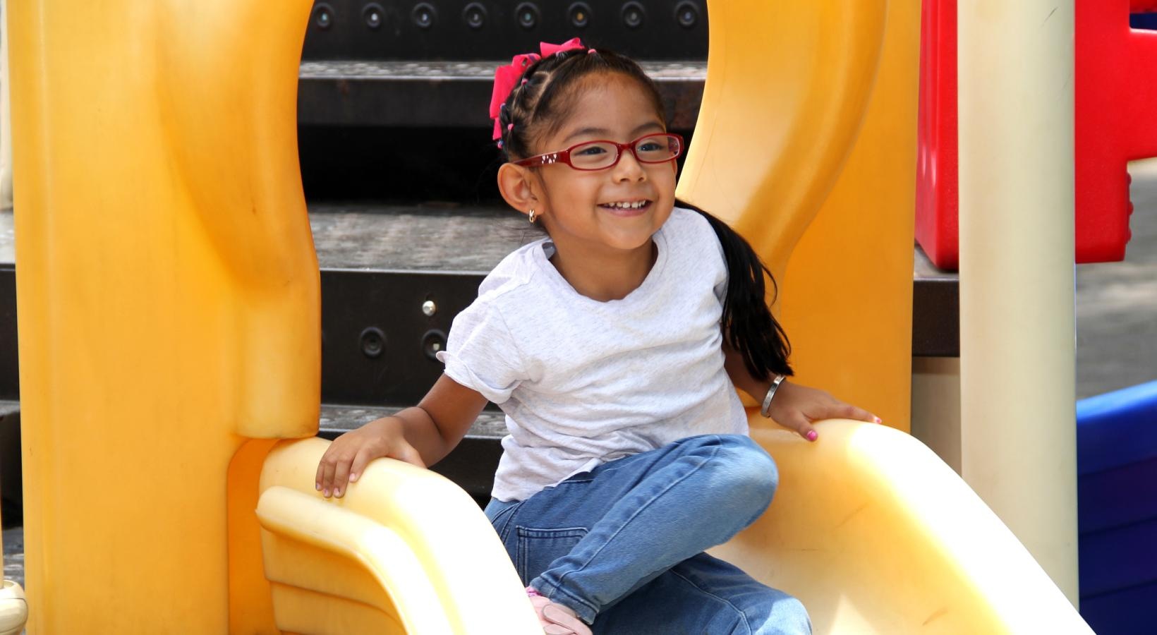Close to the center of everything a girl sitting on a playground slide