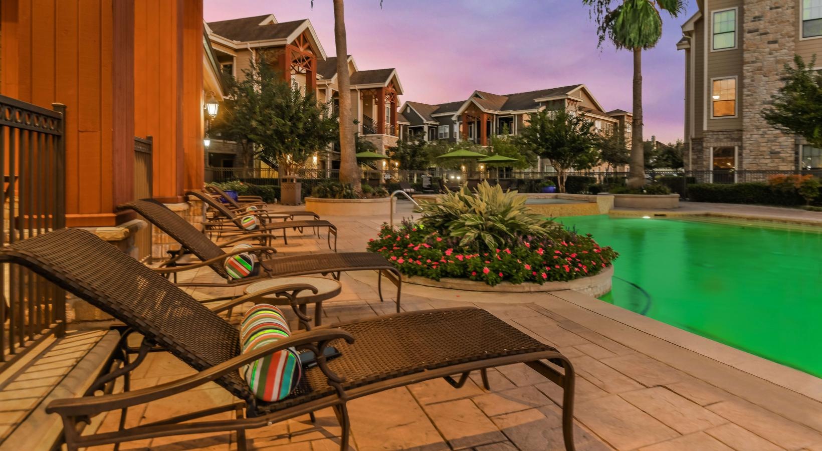 Relax and unwind poolside a pool with lounge chairs and palm trees next to it